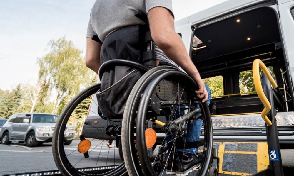 A man in a wheelchair loading a wheelchair onto a bus.